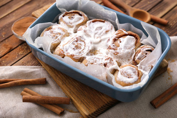 Baking dish with delicious cinnamon buns on board