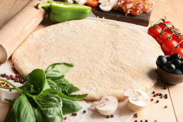 Raw dough with ingredients for pizza on table
