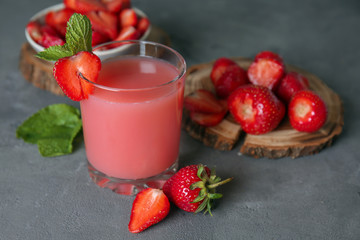 Glass with tasty strawberry starch drink on grey table