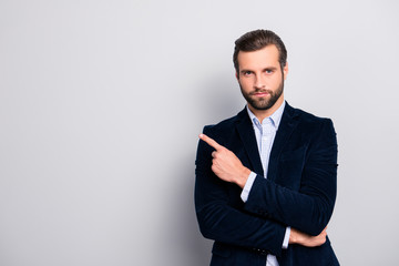 Portrait of handsome serious strict concentrated focused wealthy masculine virile elegant attractive banker with modern haircut pointing on empty blank space isolated on gray background copyspace
