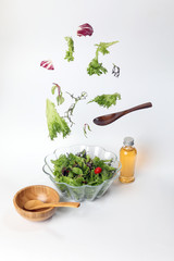 Mix leafy vegetable salad green purple lettuce glass bowl elevated flying dropping
