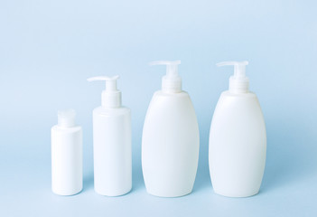 Cosmetic bottle containers on a blue minimalistic background flat lay. Blank label for branding mock-up. Natural beauty product concept.