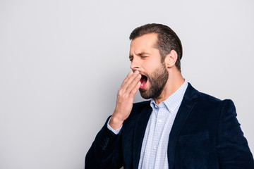 Side profile half-turned portrait of exhausted handsome professional expert yawning marketer covering mouth with a palm, formal outfit blazer checkered shirt, isolated on gray background copy-space