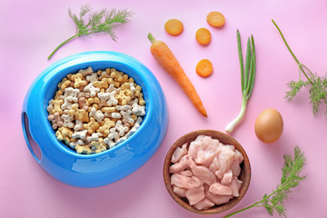 Bowls with pet food and natural products on color background