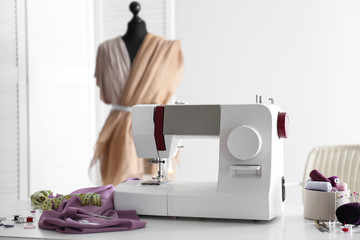 Sewing machine with accessories on table in tailor's workshop