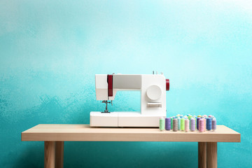 Sewing machine with threads on table against color background