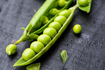 Opened pods of peas on black, macro