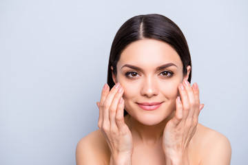 Natural nude charming woman applying lotion cream on cheekbones for flawless smooth soft skin,...