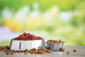 Bowls with pet food on table against blurred background
