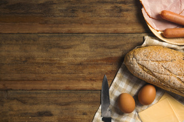 flat lay of various ingredients for breakfast on wood background, bread, egg, sausage, ham, and cheese set on background