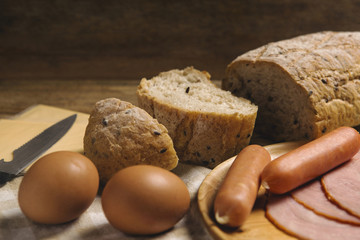 various ingredients for breakfast on wood background, bread, egg, sausage, ham, and cheese set on background