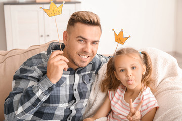 Happy father and daughter playing with party decor at home