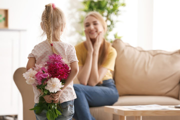 Cute little girl hiding bouquet of flowers for mother behind her back