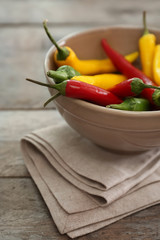 Bowl with fresh chili peppers on wooden background