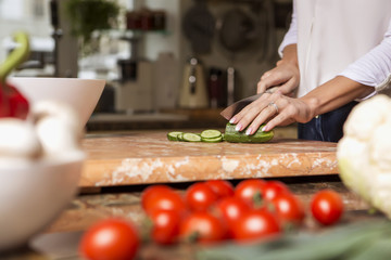 Beautiful young brunette woman in casual outfit cooking in the kitchen in her home. Luxury rich interior