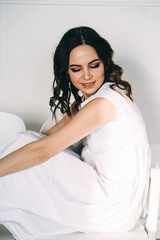 Portrait  of beautiful brunette sitting in a white dress. Vertical orientation.