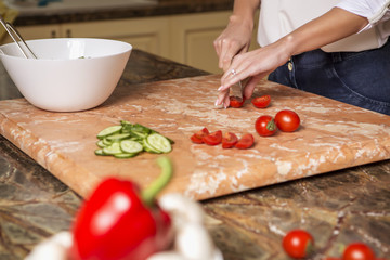 Beautiful young brunette woman in casual outfit cooking in the kitchen in her home. Luxury rich interior