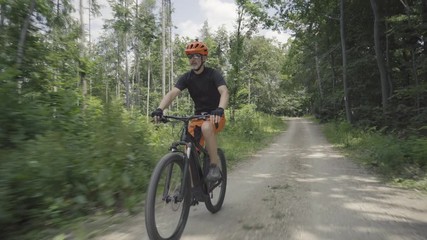 4K video man cycling on e mountain bike on forest road
