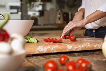 Beautiful young brunette woman in casual outfit cooking in the kitchen in her home. Luxury rich interior