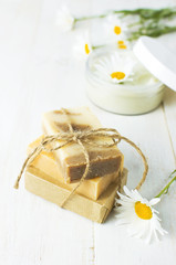 Fototapeta na wymiar Natural cosmetics, handmade soaps, face and body cream with chamomile flower on a light background. Spa concept organic cosmetic. Natural beauty product.