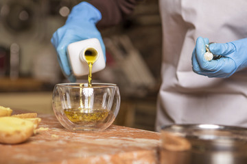 Beautiful young brunette woman in casual outfit cooking in the kitchen in her home. Luxury rich interior