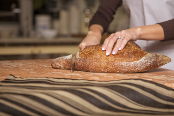 Beautiful young brunette woman in casual outfit cooking in the kitchen in her home. Luxury rich interior