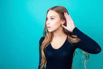portrait of a young attractive happy woman with blonde hair and makeup eavesdrops whispers a secret...