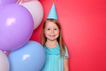 Fototapeta na wymiar Cute little girl with balloons on color background. Birthday celebration