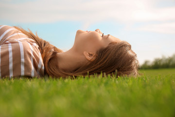 Young woman relaxing on green grass outdoors