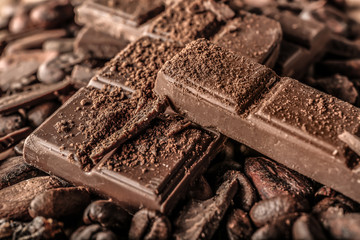 Tasty milk chocolate, coffee beans and cocoa products, closeup