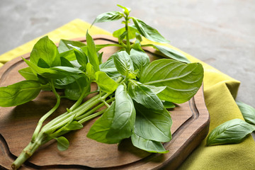 Wooden board with fresh basil on table