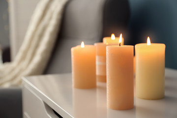Fototapeta na wymiar Commode with burning wax candles indoors