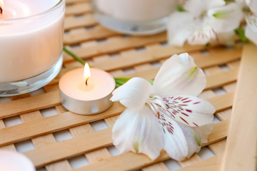 Fototapeta na wymiar Burning wax candles with flower on table