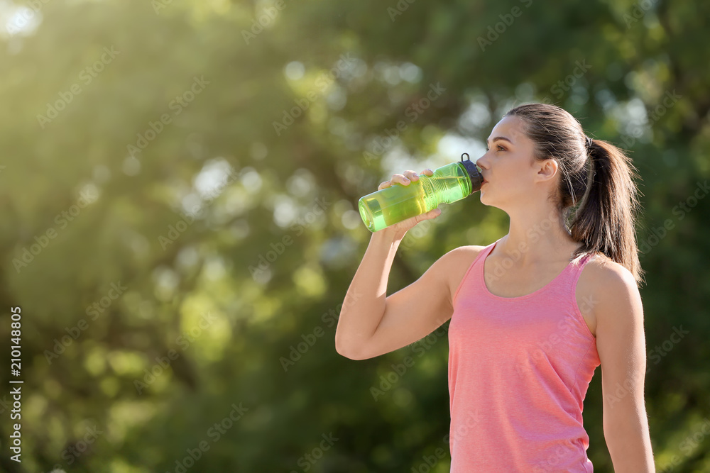 Wall mural sporty young woman drinking water outdoors