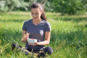 Beautiful young woman with bowl of tasty oatmeal outdoors