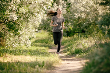 Naklejka na ściany i meble Sporty young woman running outdoors