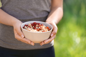 Young woman with bowl of tasty oatmeal outdoors, closeup