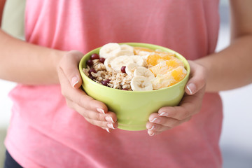 Young woman with bowl of tasty oatmeal, closeup