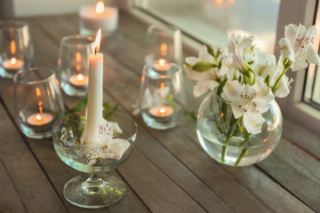 Beautiful burning candles in glasses on wooden windowsill