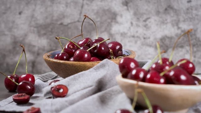 Red fresh cherries in bowls and a bunch of cherries on the table.
