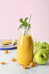 Bottle of fresh tasty smoothie and ingredients on table