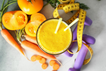 Glass of fresh tasty smoothie with ingredients, dumbbells and measuring tape on table. Weight loss concept