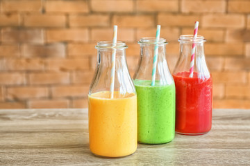 Bottles with fresh tasty smoothies on wooden table