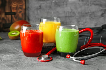 Glasses with fresh tasty smoothies and stethoscope on table. Health care concept