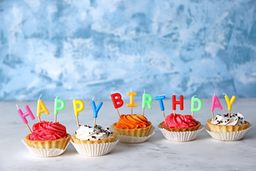 Colorful birthday cupcakes with candles on table