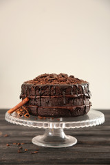 Stand with delicious chocolate cake on wooden table