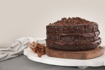 Board with delicious chocolate cake on table