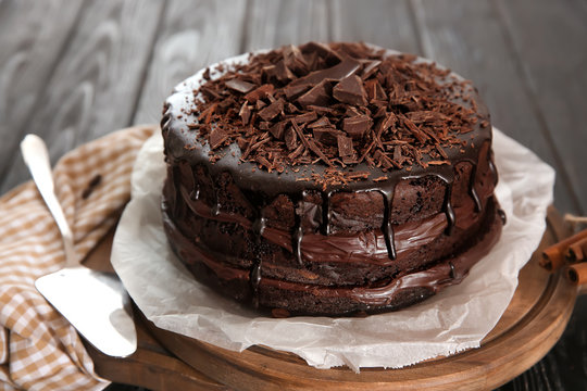 Board with delicious chocolate cake on wooden table