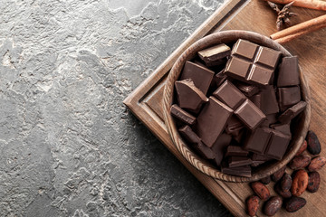 Bowl with tasty milk chocolate on grey textured background