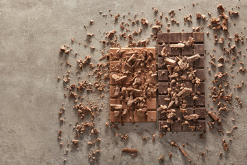 Tasty chocolate bars and chunks on grey background